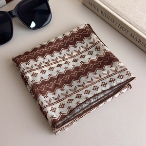 Detail of brown polka dot printed silk scarf with wave patterns and precision edging