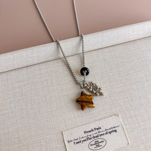 Detail of star-shaped tiger eye stone pendant and silver stainless steel chain necklace