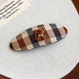 Detailed macro view of a brown plaid hair clip with a cute 3D flocked teddy bear detail