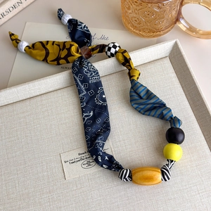 Detailed macro view of bohemian cloth stitching necklace with marble and wooden beads