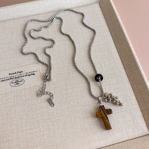 Macro shot of a tiger eye cross pendant with silver metal beads on a box chain necklace