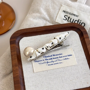 Close-up of a French vintage polka dot fabric hair clip with a large glossy pearl