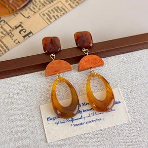 Detail of amber resin and wood drop earrings on vintage newsprint and linen