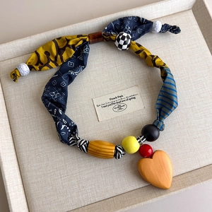Detail of fabric patchwork necklace with wooden beads and a heart-shaped pendant