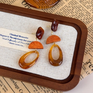 Close-up of vintage resin drop earrings with brown stones and amber oval rings