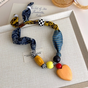 Detailed close-up of handmade fabric patchwork necklace with wooden beads and heart pendant