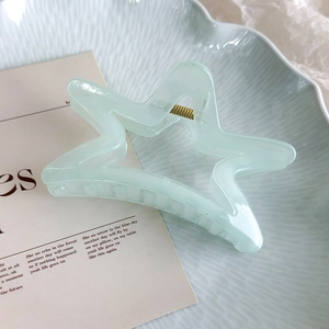 Détail de la pince à cheveux en étoile vert menthe sur assiette bleue sous lumière douce
