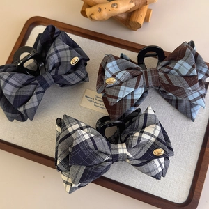 Detail of plaid bow hair claws with gold 'LOVE' tag on linen display tray
