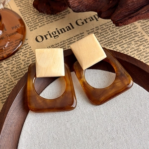 Detail view of vintage geometric wood and amber resin square drop earrings on a tray