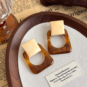 Detail of square wood and amber resin drop earrings in a vintage aesthetic setting
