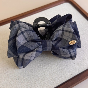 Detail of the navy blue plaid bow hair claw with a gold metal plate engraved with love