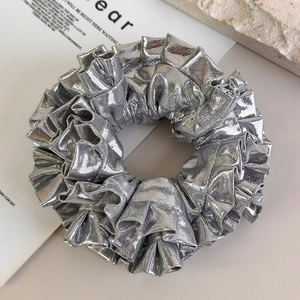 Dettaglio macro dell'elastico per capelli argento metallizzato con texture plissettata