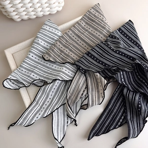 Detailed view of striped cotton triangle scarves in black, white, and grey colorways