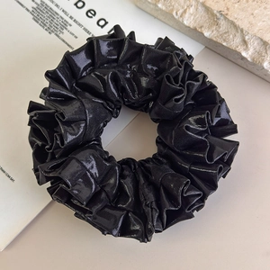 Dettaglio di elastico per capelli nero metallizzato laser con trama a pieghe