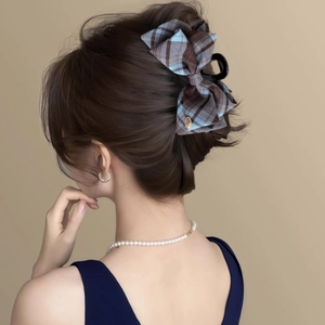 Elegant plaid bow hair claw clip for women in blue and brown pattern on a dark base