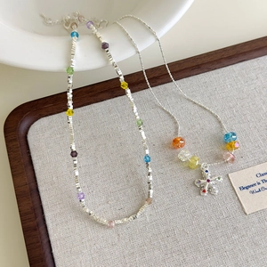 Colorful crystal star and silver beaded necklace set with flower pendant on linen tray