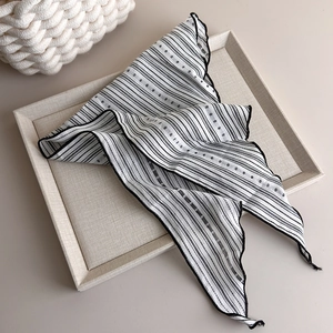 Detail shot of striped chiffon scarf with delicate ruffle edges on a beige tray