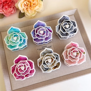 Dettaglio delle mollette per capelli a camelia colorate in acetato con trama marmorea