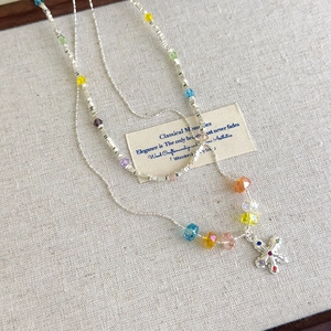 Detailed close-up of a multi-layer silver necklace with colorful crystal beads and a cross charm