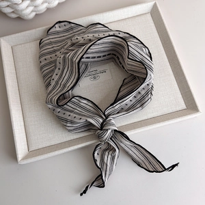 Detailed texture of black and white striped scarf on minimalist cotton linen tray