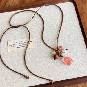 Détail macro du collier vintage avec pierre rose, perle de bois et perle sur lin