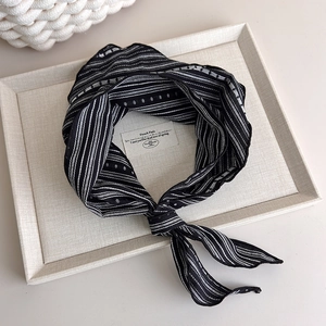 Detail of a vintage striped silk scarf with geometric patterns tied in a chic French knot
