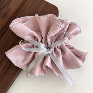 Detailansicht von rosa Satin-Haargummi mit Silberkanten und grauer Bandschleife