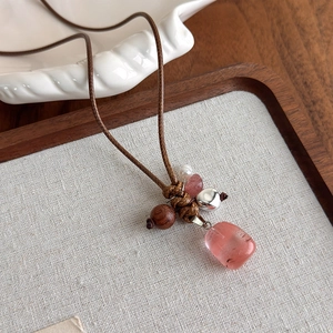 Gros plan d'un collier fait main avec pierre rose, perle en bois et perle sur ficelle