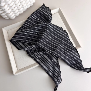 Artistic detail of black and white striped twilly scarf on beige textured board