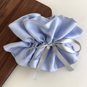 Detail eines hellblauen Satin-Haargummis mit silberner Schleife und Perlglanz