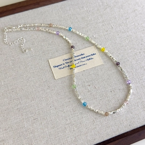 Close-up of colorful crystal star necklace with silver accents on a vintage card