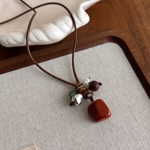 Détail du collier ethnique vintage avec pierre rouge, perle en bois et breloque cœur