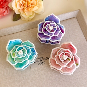 Dettaglio di fermagli per capelli camelia in blu, viola e rosa con texture marmorea perlata
