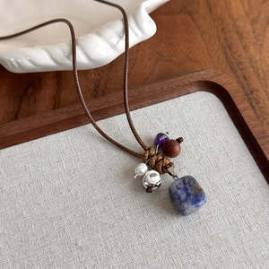 Détail d'un collier bohème avec pierre de marbre bleue et perles en bois tressées
