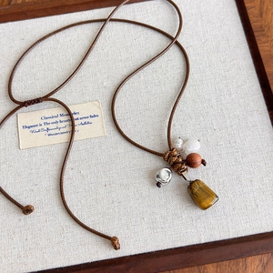 Détail du collier en corde cirée réglable avec œil de tigre et perles en bois