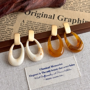 Dettaglio di orecchini vintage ovali in resina crema e ambra con perno dorato opaco