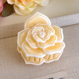 Dettaglio macro della molletta per capelli a camelia crema con petali di acetato