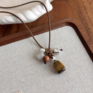Vue détaillée du collier bohème avec pierre œil de tigre, perles en bois et cœur en argent