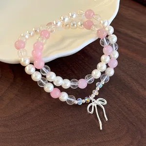 Elegant double-layered pearl bracelet with pink beads and a silver bow pendant charms