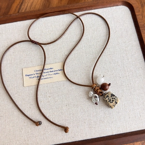 Détail d'un pendentif bohème en pierre avec perles en bois sur cordon ciré marron