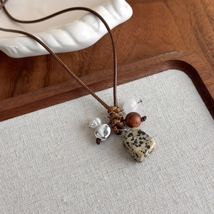 Détail de la pierre dalmate et des perles en bois sur un collier tissé de style rétro
