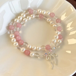 Detail of double-layer beaded bracelet with pink gems, pearls and silver bow charm