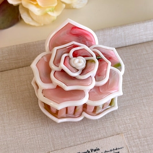 Dettaglio del fermaglio a camelia con petali in acetato marmorizzato rosa e rilievo 3D