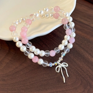 Detail of double-layer beaded bracelet with pearl, pink beads and silver bow charm