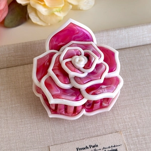 Dettaglio del fermaglio per capelli a camelia con trama marmorizzata rosa elegante