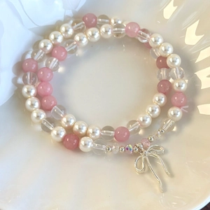 Detail of double-layer beaded bracelet with pearls, pink crystals and silver bow charm