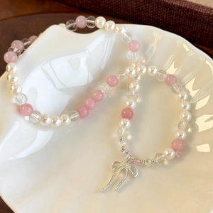 Close-up of pearl and pink crystal layered bracelet with a silver bow charm