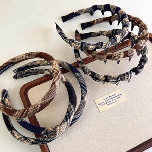 Detail of plaid fabric headbands with non-slip teeth and handmade labels on display