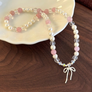 Detail of beaded pearl bracelet with a silver bow tassel charm on a shell plate