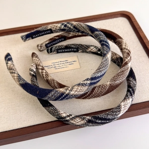 Close-up of three checkered fabric headbands with handmade label on a display tray